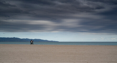 Fototapeta na wymiar poetto beach with two people walking. Freedom concept