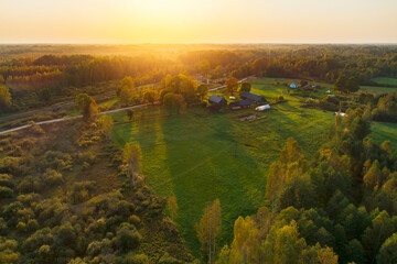 Soft colourful sunset light over the forest and countryside farm in distance.