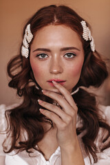 Fototapeta na wymiar Portrait of charming green-eyed girl with pearl hairpins in wavy hair
