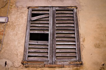 A ruined window with a broken wooden shutter in a medieval italian village (Corinaldo, Marche, Italy, Europe)