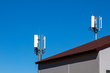 Roof with 4G, 5G transmitters. Cellular base station with transmitter antennas against a blue sky