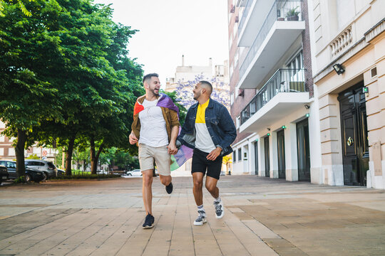 Gay couple holding their hands and running together.