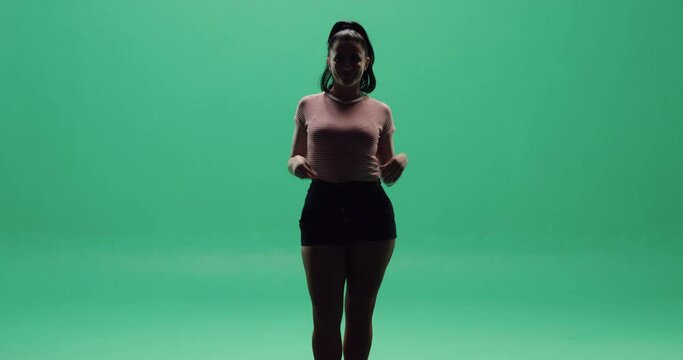 Studio, slow motion, a silhouette of a young woman dancing in a shadow against a green screen