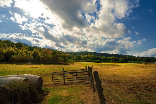 This idyllic image shows a rural stable landscape with beautiful clouds overhead. 