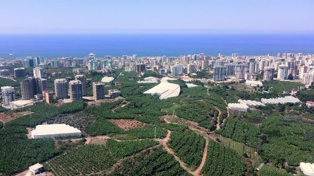 City of Mahmutlar from the banana farms and view at residence apartment buildings on the sea shore. Aerial view from a Drone perspective.