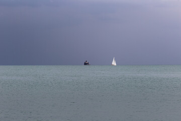 Dark skyline with sailboat in distance on dark overcast day