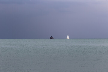 Dark skyline with sailboat in distance on dark overcast day