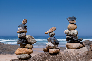 Fototapeta na wymiar Group of towers from small stones balanced on the beach with the sea in the background