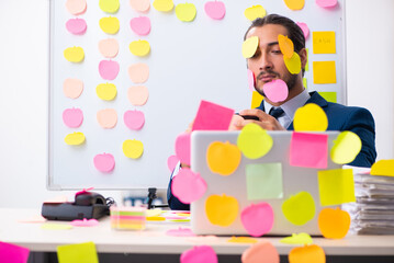 Young male employee in conflicting priorities concept