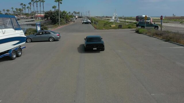 Aerial, tracking, a black 1968 Camaro about to leave parking, San Diego, USA