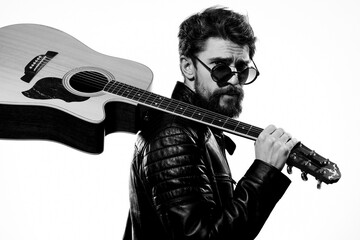 A man holds a guitar in his hands music emotions black leather jacket dark glasses studio light background