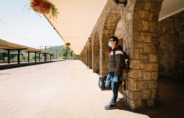 Person with mask waiting on train station platform