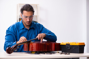 Young male repairman repairing cello