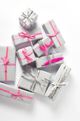 holiday layout. Christmas gifts are wrapped in beautiful gray paper and decorated with silver and pink ribbons and decor on a white background. top view, flat lay