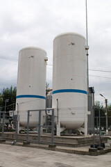 Big white gas cylinders behind the fence. Balconies on the city street.
