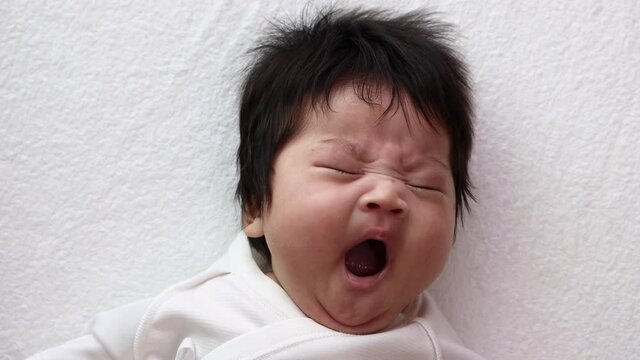 大きな欠伸している生後13週の赤ちゃんの顔