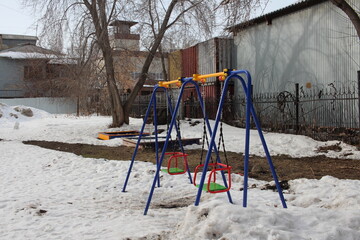 empty children's swings on the street in the courtyard in winter
