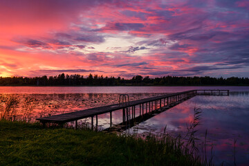 Incredible sunset landscape with a wooden pier on a stunning forest lake