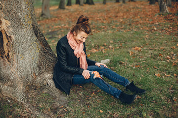 Woman with a leg injury. The wounded girl sitting by the tree. The wound is bleeding.