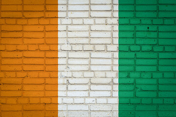 National flag of Cote d'ivoire depicting in paint colors on an old brick wall. Flag  banner on brick wall background.