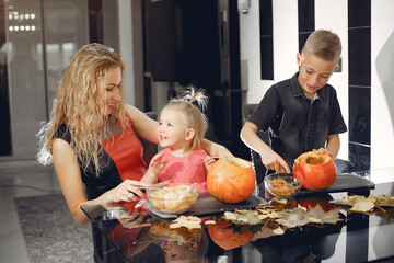 Family in a kitchen. People prepares to halloween. Family cuts pumpkins.