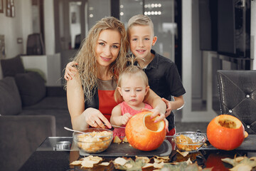 Family in a kitchen. People prepares to halloween. Family cuts pumpkins.