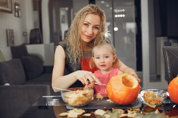 Family in a kitchen. People prepares to halloween. Family cuts pumpkins.