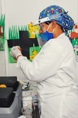 BLACK DOCTOR WITH A FACE AND COVER READING A VACCINE