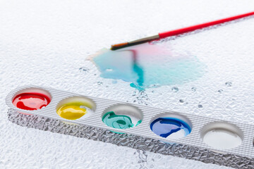 Close-up of a basic color palette. Blurred background of a brush on a stain of paints. It evokes...
