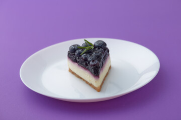 blueberry cheesecake  on white plate on violet background