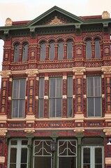 Fototapeta premium Vertical of historic building in Galveston Island, Texas with colorful brick designs, green metal doors, tall windows, old fashion street light