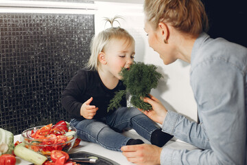Family in a kitchen. Mother with little daughter. People with vegetables