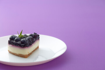 blueberry cheesecake  on white plate on violet background