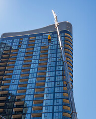 Obraz premium A person working up on a high rise crane cradle on the side of a tall building 