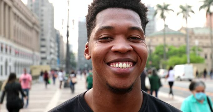 Trendy young black African man smiling at camera in downtown city, real people