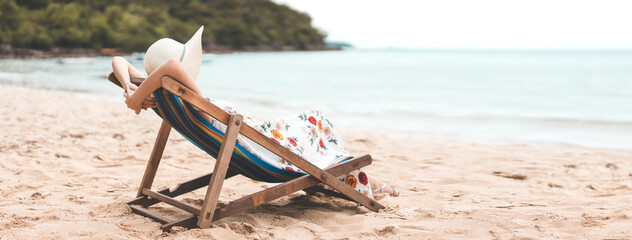 Rear view of young adult tourist asian woman relax sitting on outdoor beach chair at sea