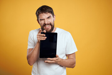 Man with a tablet on a yellow background in a white t-shirt new technologies businessman touch screen touchpad