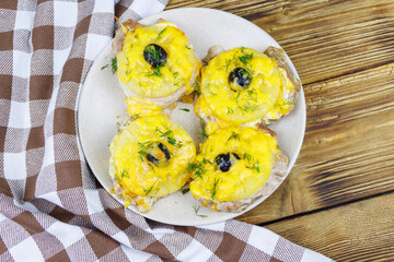 Pieces of baked pork with pineapple, cheese and olive on a wooden table. Top view