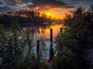 Beautiful Riverside Sunrise with Reflections and Old Jetty Pylons