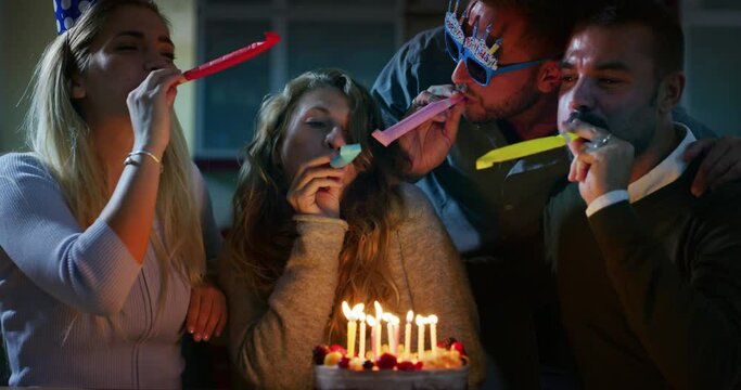 Authentic shot of happy friends are having fun during their friend birthday celebration party at home. Birthday girl is blowing a candles of a cake.Concept of friendship, holidays,celebration, present