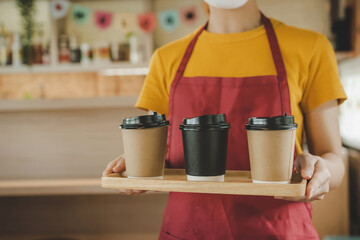 friendly waitress woman wearing protection face mask waiting for serving hot coffee cup to customer in cafe coffee shop, cafe restaurant, service mind, new normal, food and drink delivery concept