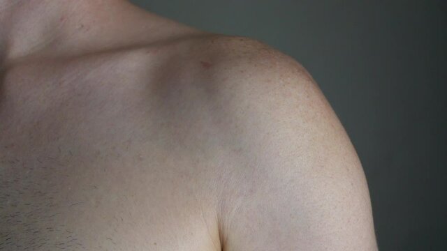 A nerve involuntarily and repeatedly twitches in a man's shoulder and upper arm, shown isolated and up close.