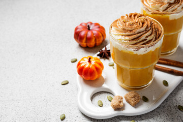 Pumpkin spice latte in a glass with cinnamon, nutmeg and whipped cream.