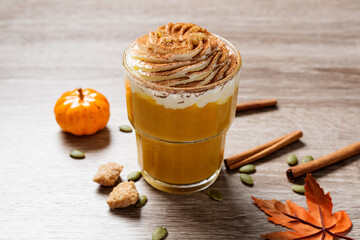 Pumpkin spice latte in a glass with cinnamon, nutmeg and whipped cream.