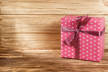 Gift box with ribbon on wooden background