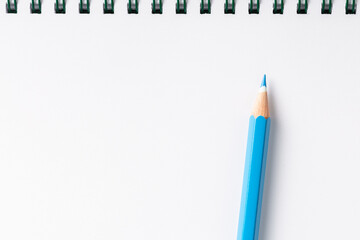 notebook with blue pencil on white table top view.