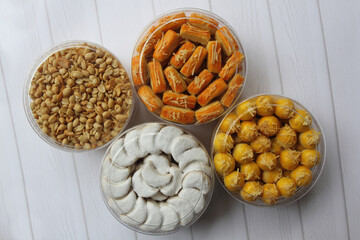 Four jars of Nastar (Dutch pineapple tarts), Kaasstengels (Dutch cheese finger cookies), Vanillekipferl (Austrian crescent shaped vanilla biscuits), and Fried Peanuts on a table.