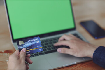 Man using blank laptop and credit card sending massages shopping online.