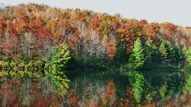 Wide, autumn forest reflected in the calm waters of Fawn Lake, North Carolina, USA