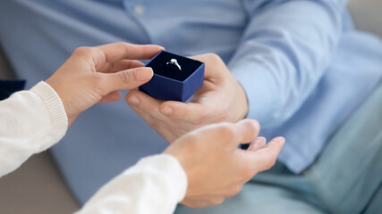 I agree! Young woman taking engagement ring from hand of man accepting his proposal demonstrating she is agree to marry him, husband giving present to wife on occasion of wedding anniversary, close up